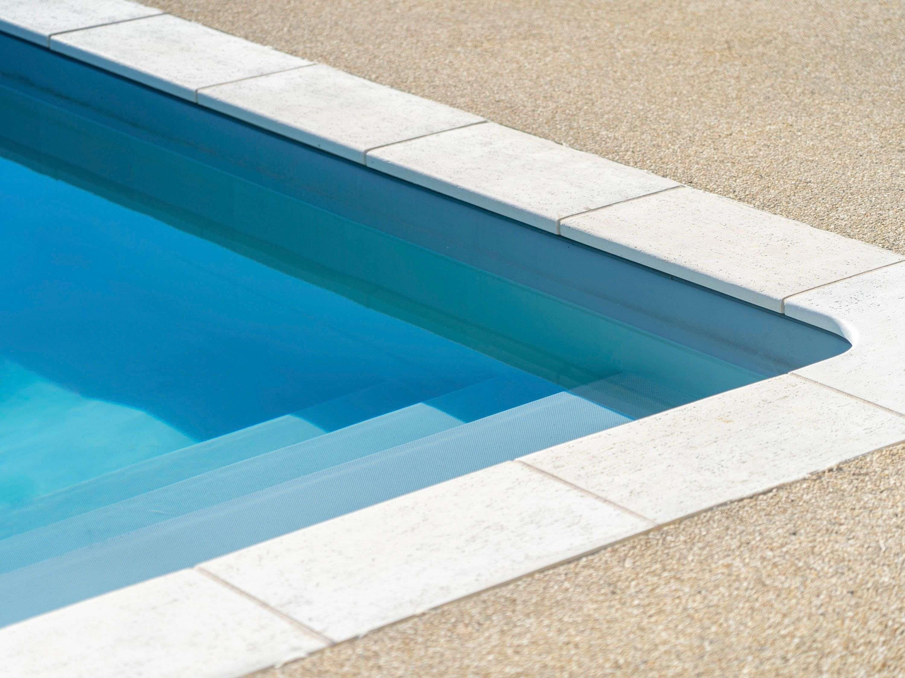 A swimming pool with a tiled edge and a textured ground surface.