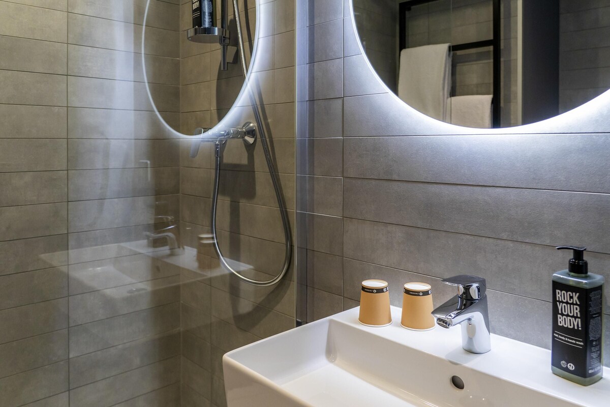 Ein modernes Badezimmer mit einem weißen Waschbecken, einem Spiegel und zwei Lotionflaschen.