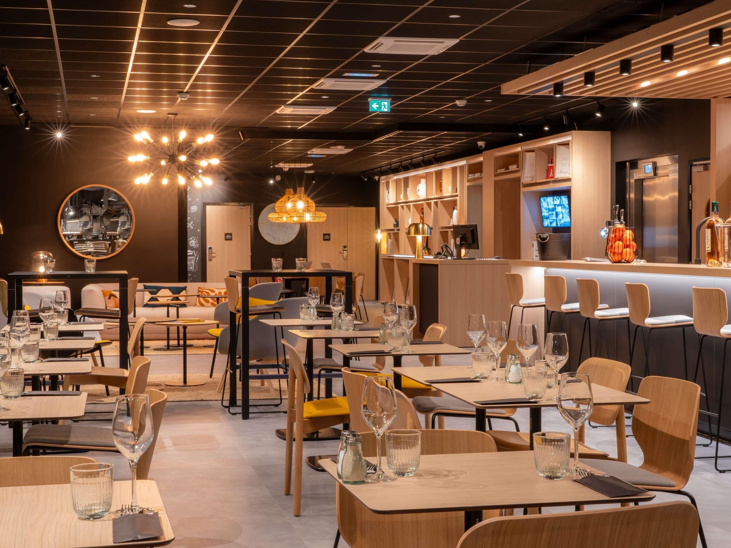 Interior de un restaurante con varias mesas, sillas y una zona de bar.