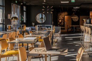 Una cafetería moderna con varias mesas y sillas, un espejo grande y una lámpara de techo original.