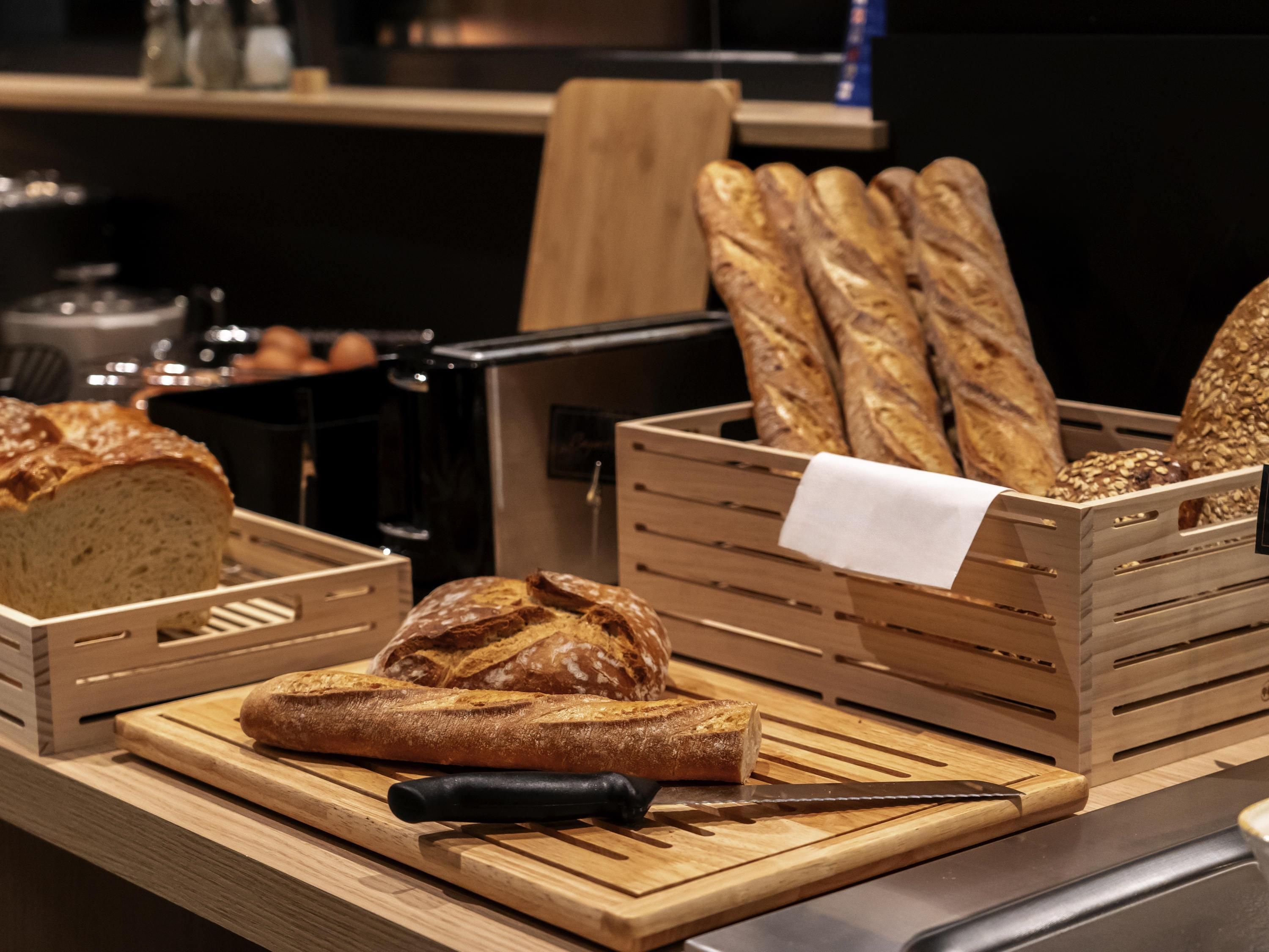 Mostrador de panadería con diversos panes y un cuchillo sobre una tabla de madera.
