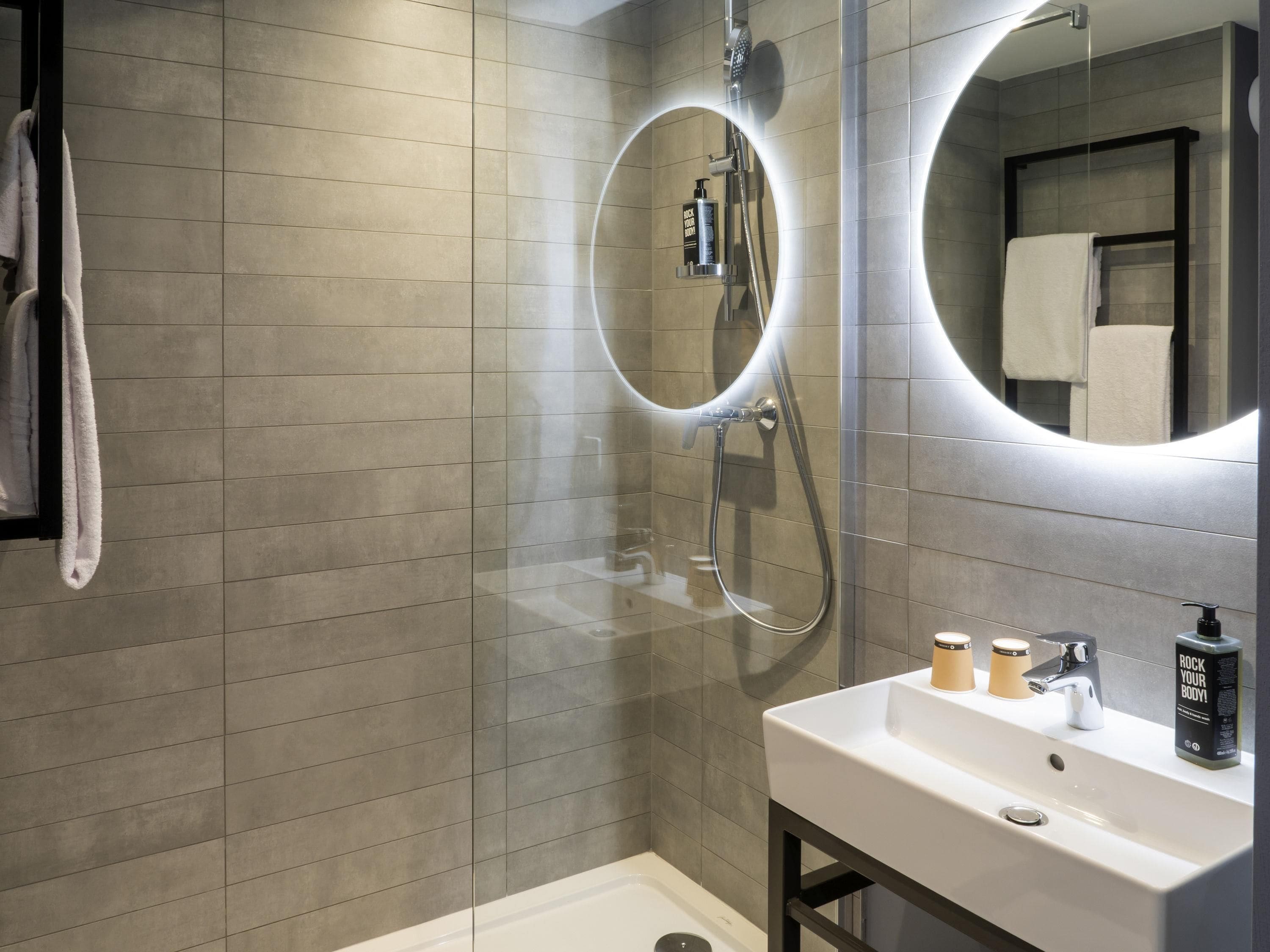 Un baño moderno con ducha, lavamanos y espejo.