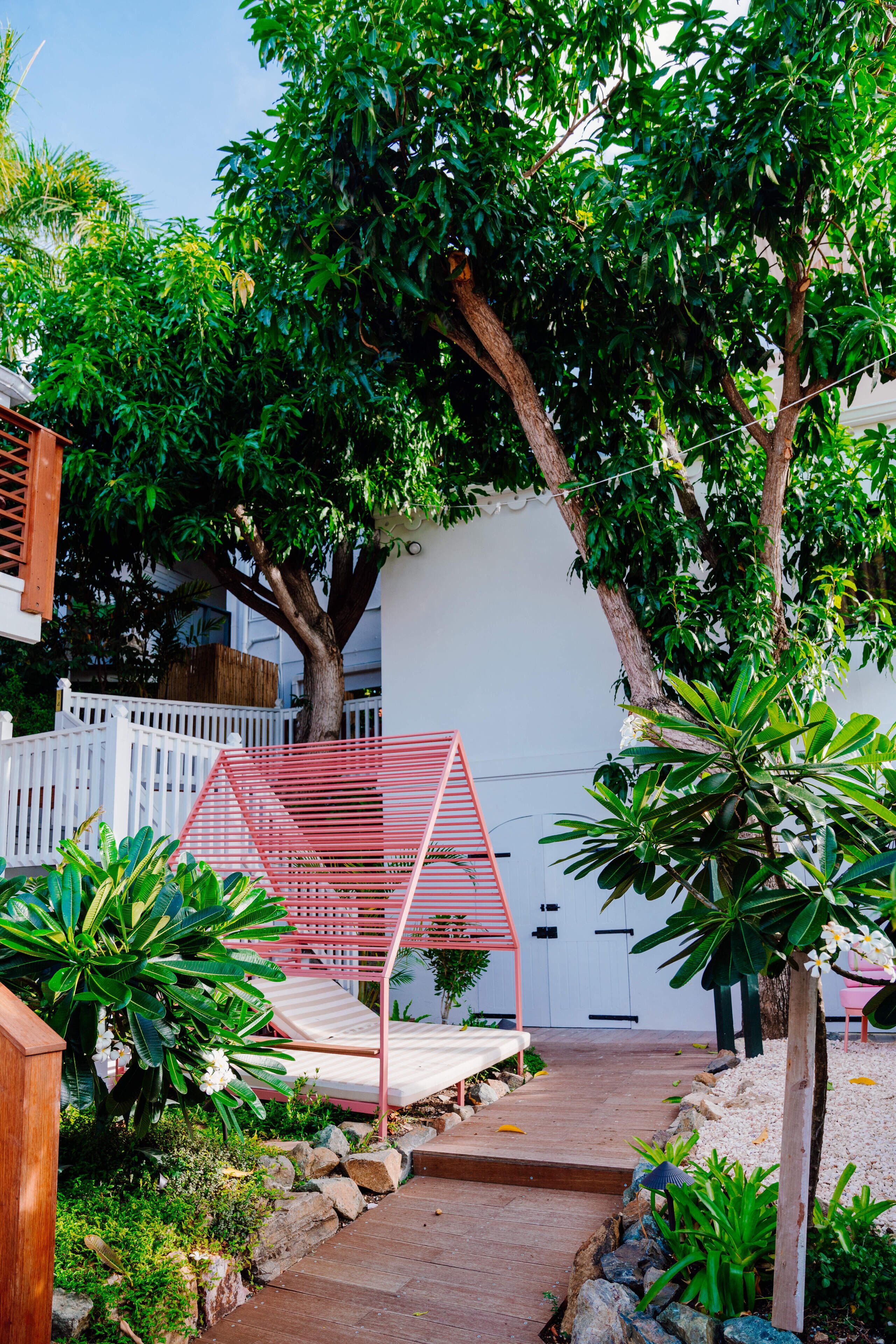 A garden with a wooden deck, a white fence, and a red metal structure.