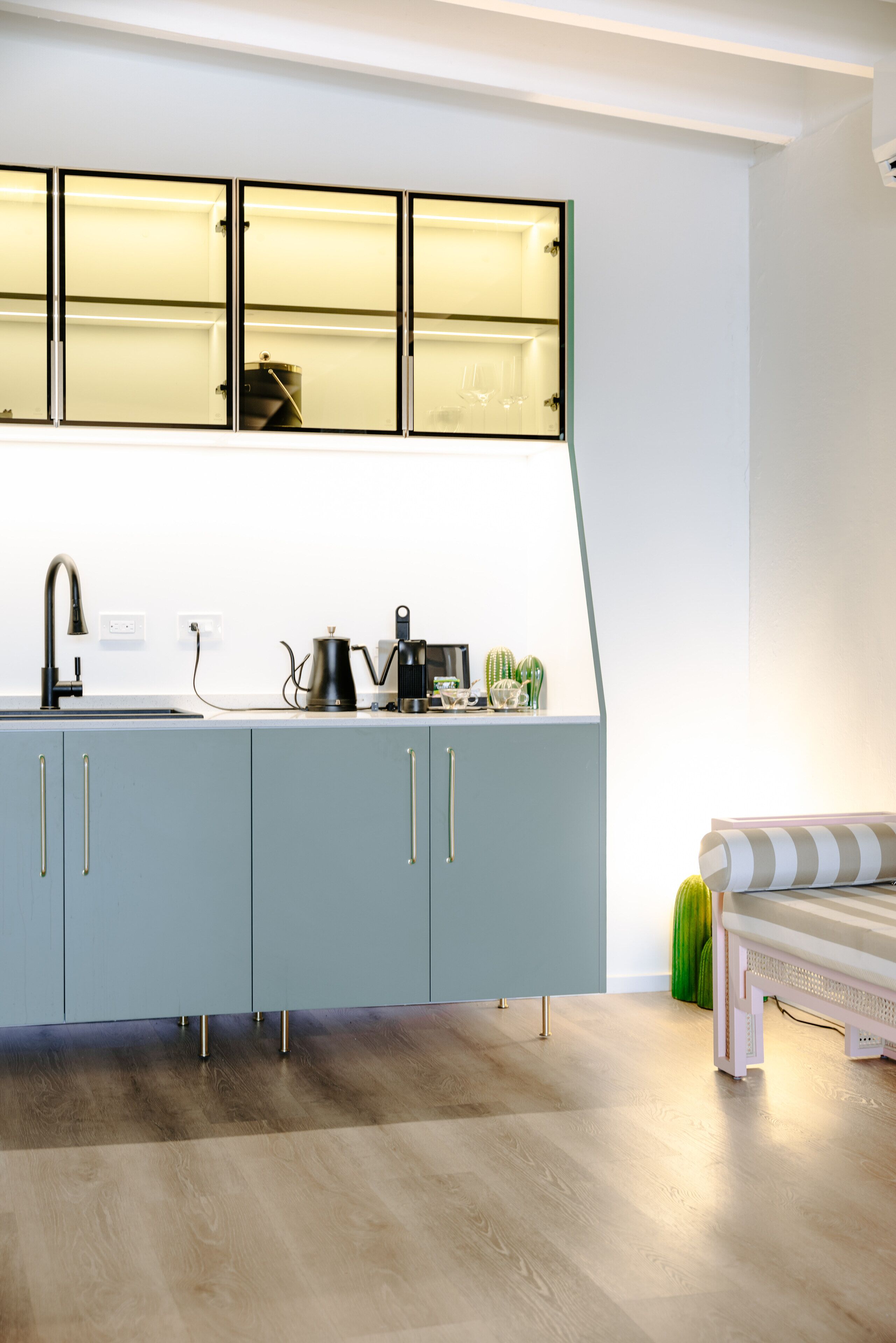 Eine moderne Küche mit einem hellblauen Schrank, einem schwarzen Wasserkocher und einer Kaffeemaschine.