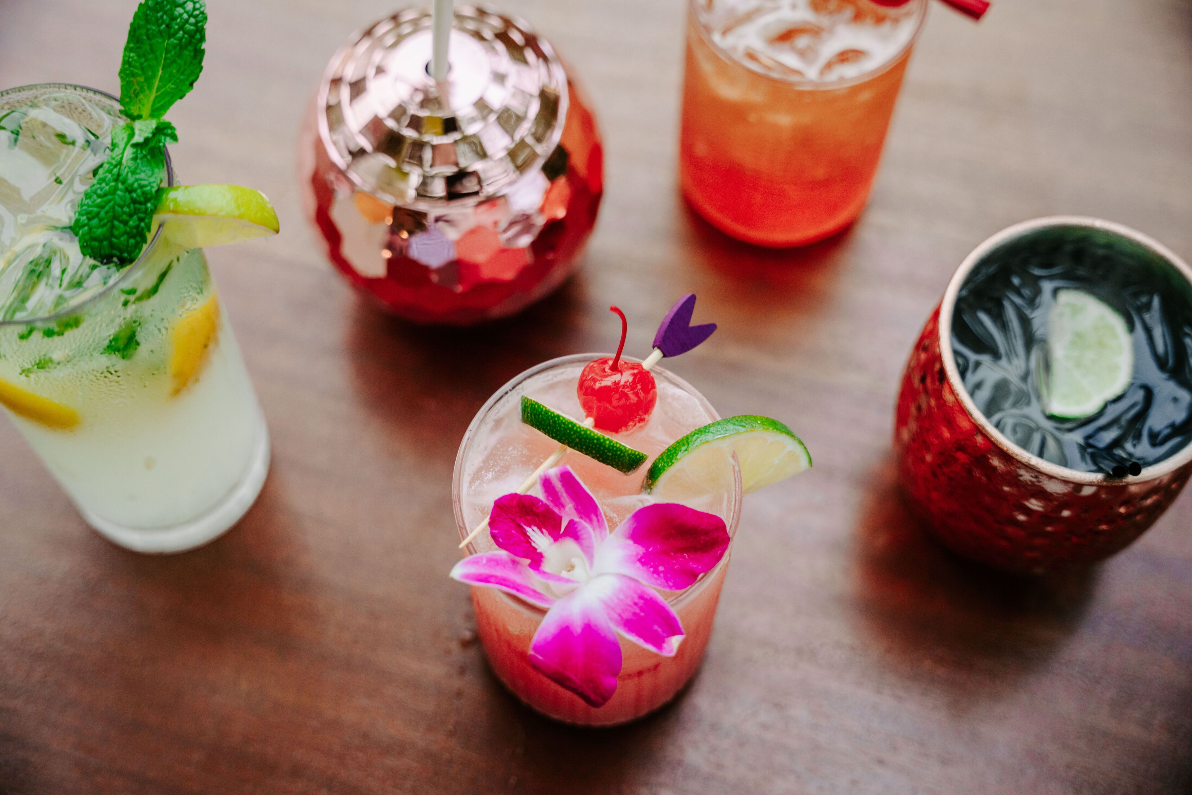 A variety of drinks with garnishes on a wooden table.