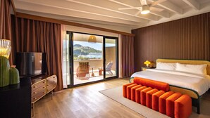 Ein Schlafzimmer mit Bett, Fernseher, einer Couch und Blick ins Freie.