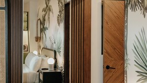 A bedroom with a wooden wardrobe, a bedside table with a lamp, and a bed with white bedding.