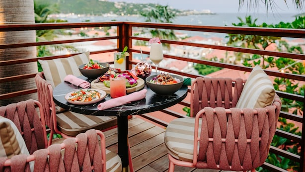 A dining table with a meal, a drink, and a view of the sea.
