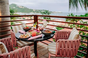 Una mesa de comedor con comida, una bebida y vistas al mar.