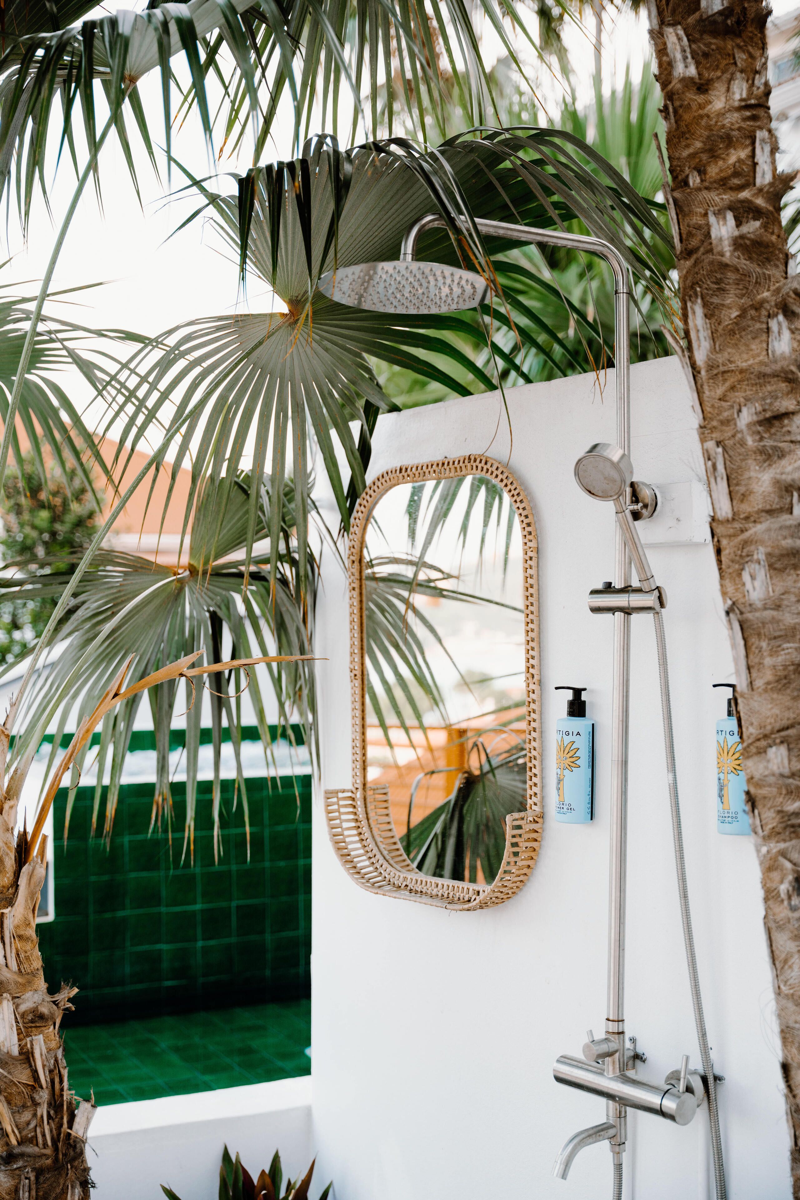 A bathroom with a shower, a mirror, and a green tiled wall.
