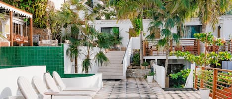 A rooftop terrace with lounge chairs, a tiled floor, and a staircase leading to an upper level.