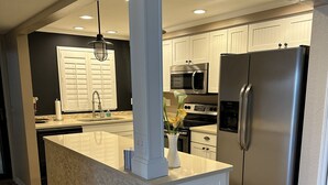 Una cocina moderna con una isla central, electrodomésticos de acero inoxidable y diseño de armarios blancos.