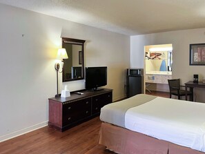 Hotelkamer met een bed, televisie, bureau, stoel, magnetron en lamp.