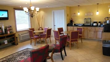 A dining area with a round table and chairs, a kitchen area with appliances, and a television mounted on the wall.