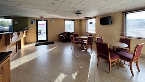 A restaurant interior with a counter, seating area, and exit door.