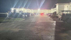 A parking lot with several vehicles and a building in the background.