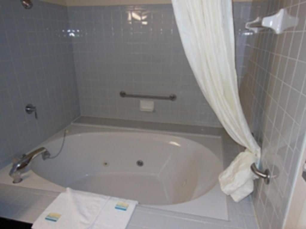 A bathroom with a bathtub, a towel, and a shower curtain.