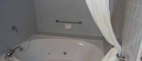A bathroom with a bathtub, a towel, and a shower curtain.