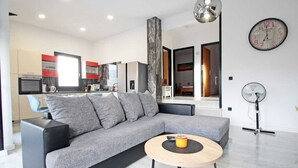 A modern living room with a grey sofa, a round wooden coffee table, and a kitchen in the background. - Attractive holiday house near the sea! (Vinjerac)