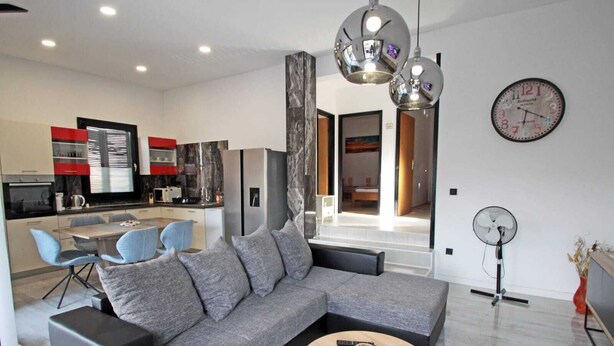 A modern living room with a grey sectional sofa, a round coffee table, and a dining area with blue chairs. - Attractive holiday house near the sea! (Vinjerac)