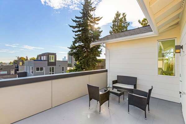 A balcony with wicker furniture and a view of the cityscape. - Vhagar's Valyria's Vista (Seattle)