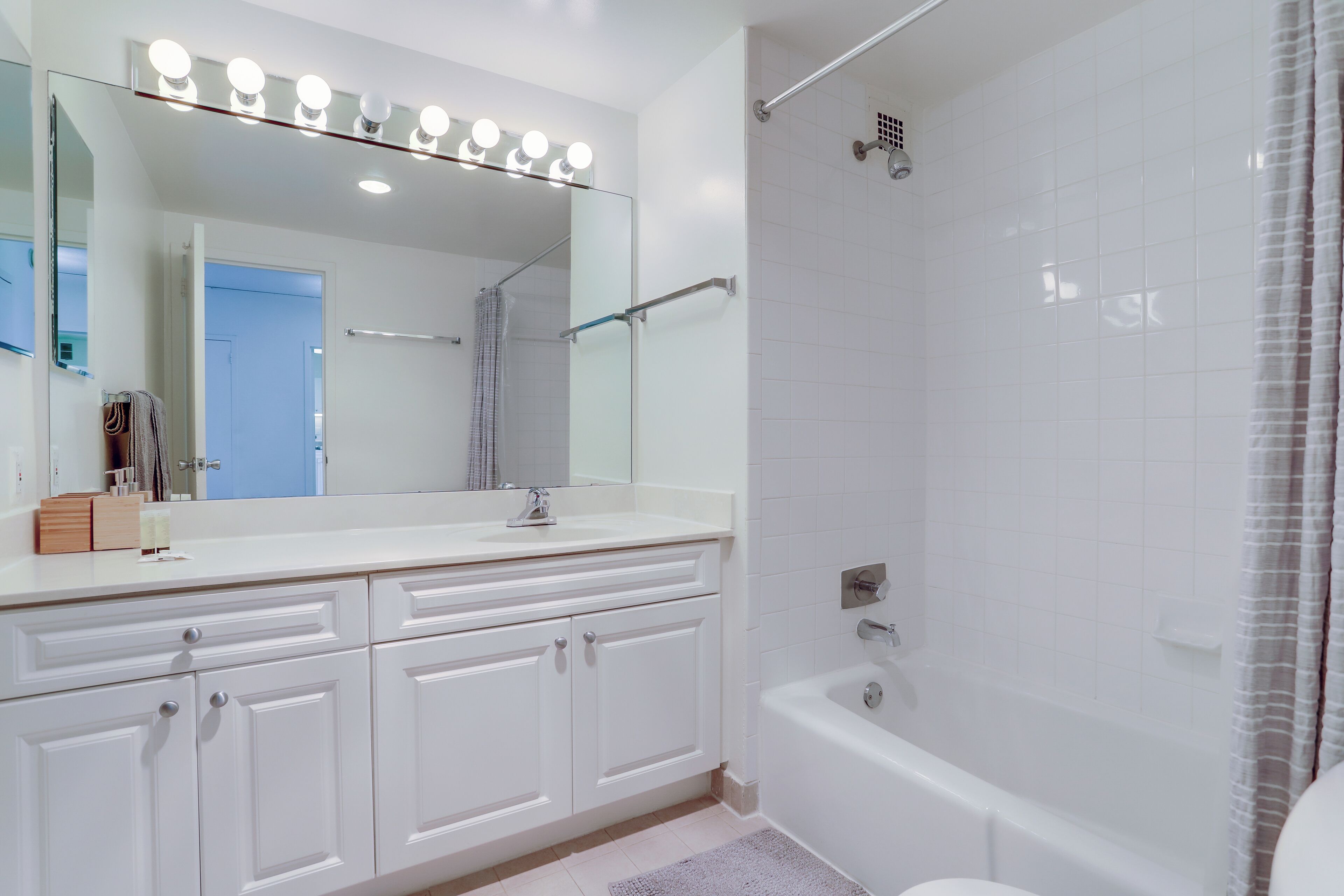Une salle de bain moderne avec un grand miroir, un meuble-lavabo et une baignoire.