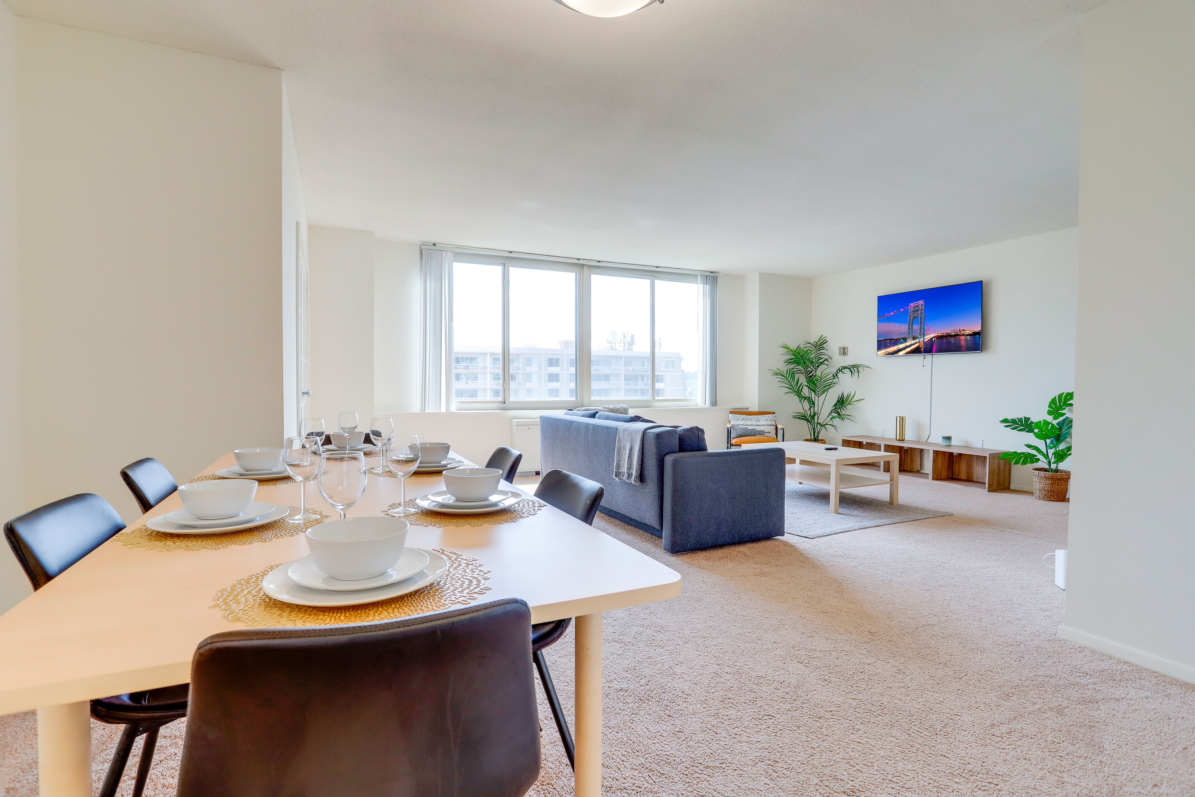 Ein modernes Wohnzimmer mit Essbereich, großen Fenstern und Blick auf die Stadt.