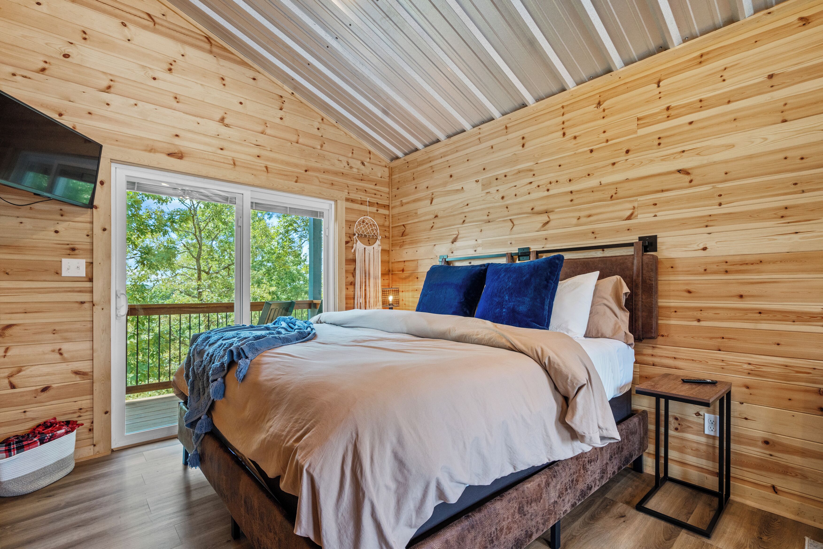 A wooden cabin bedroom with a bed, a nightstand, and a large window.