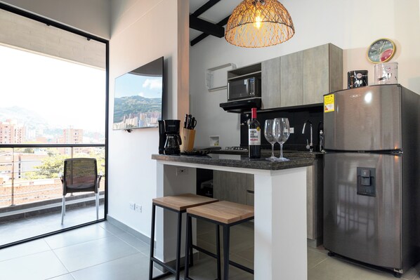 A modern kitchen with a large window, a hanging light fixture, and a view of the city.