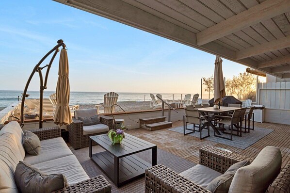 Relax in style with ocean views from this inviting outdoor lounge area featuring a deck, sofas, chairs, and dining table.