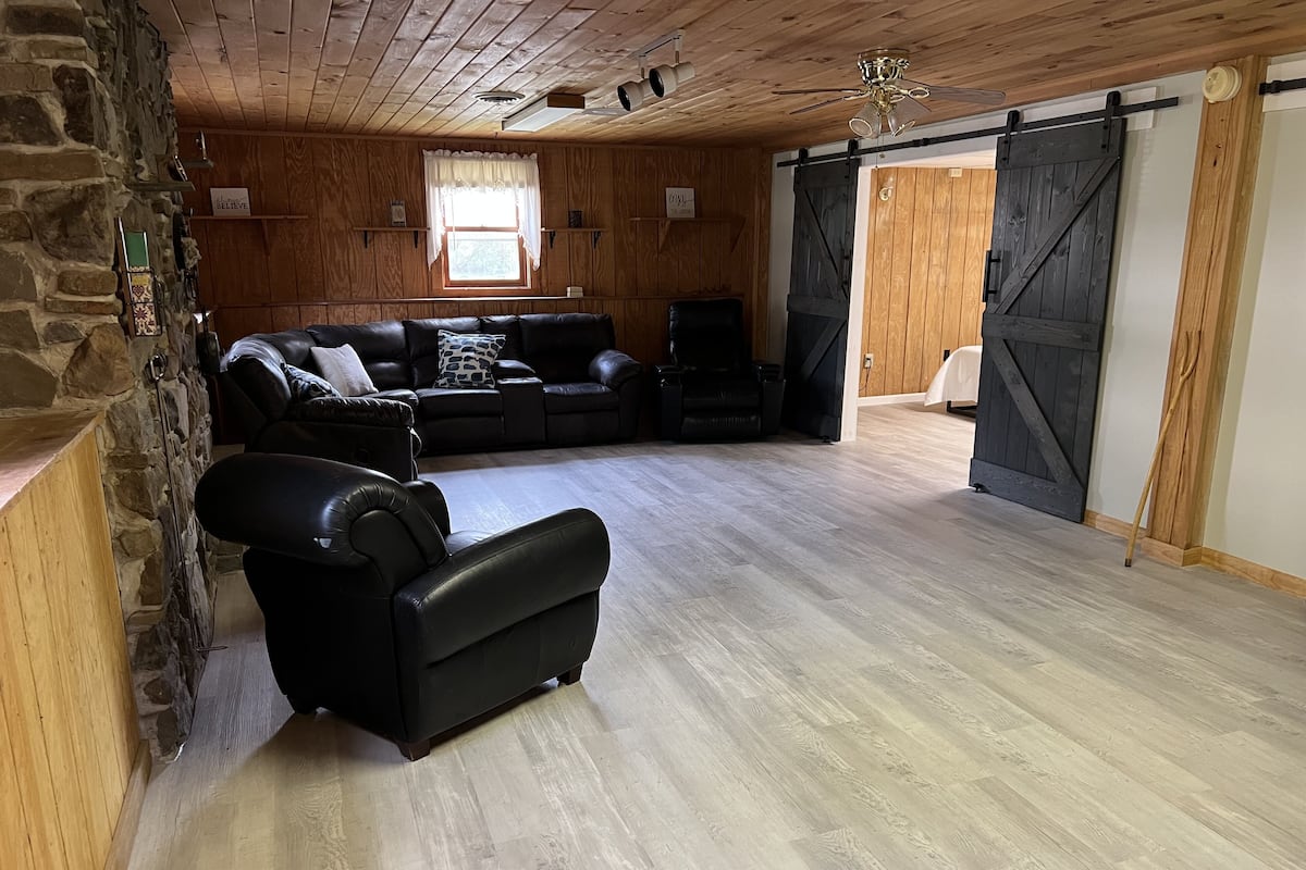 Amplia sala de estar con pared de piedra, techo de madera y un gran puerta corrediza tipo establo.