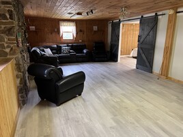 Amplia sala de estar con pared de piedra, techo de madera y un gran puerta corrediza tipo establo.