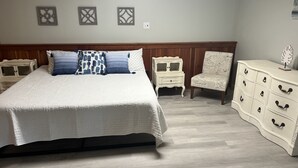 Une chambre à coucher avec un grand lit, une table de chevet, une chaise et une commode.