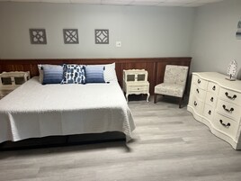 Un dormitorio con una cama grande, una mesita de noche, una silla y un aparador.