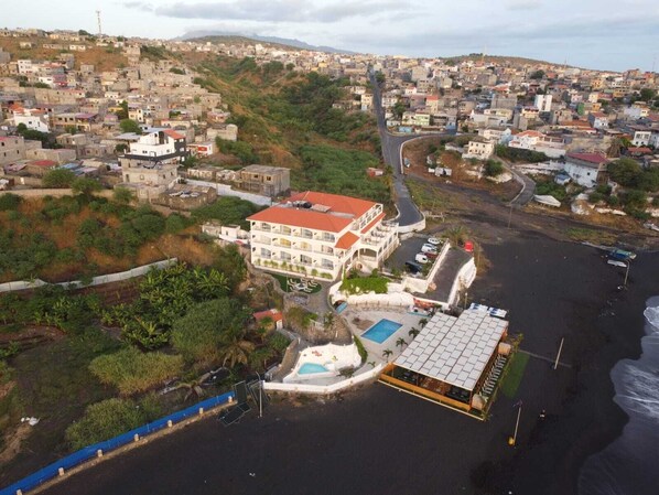 An aerial view of a coastal town with a prominent hotel featuring a swimming pool and a beachside restaurant. - Hotel Restaurant Falucho Paradise Beach (Santa Cruz)