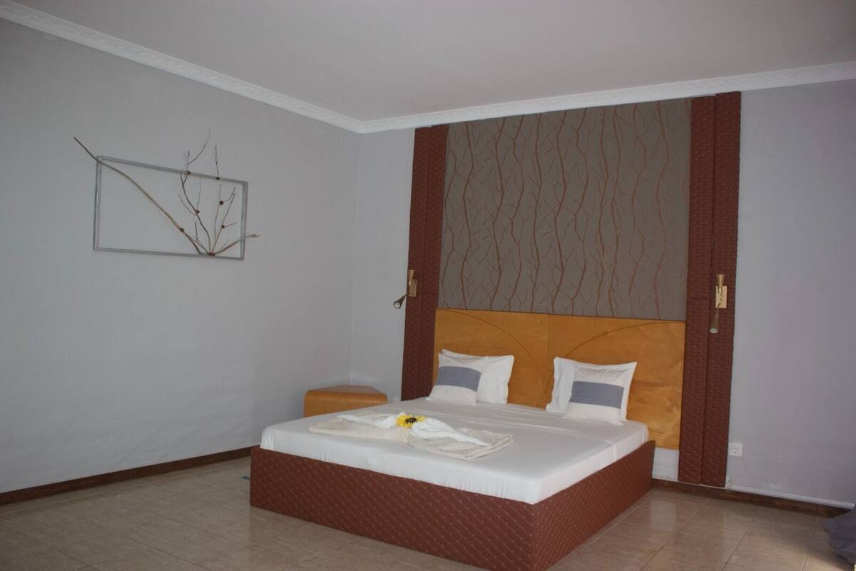 Ein Hotelzimmer mit einem großen Bett, einem Nachttisch und einem an der Wand hängenden Kunstwerk.