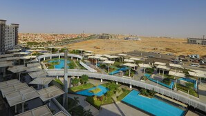 Een modern hotel met meerdere zwembaden, een overdekte doorgang en uitzicht op een woestijnlandschap.