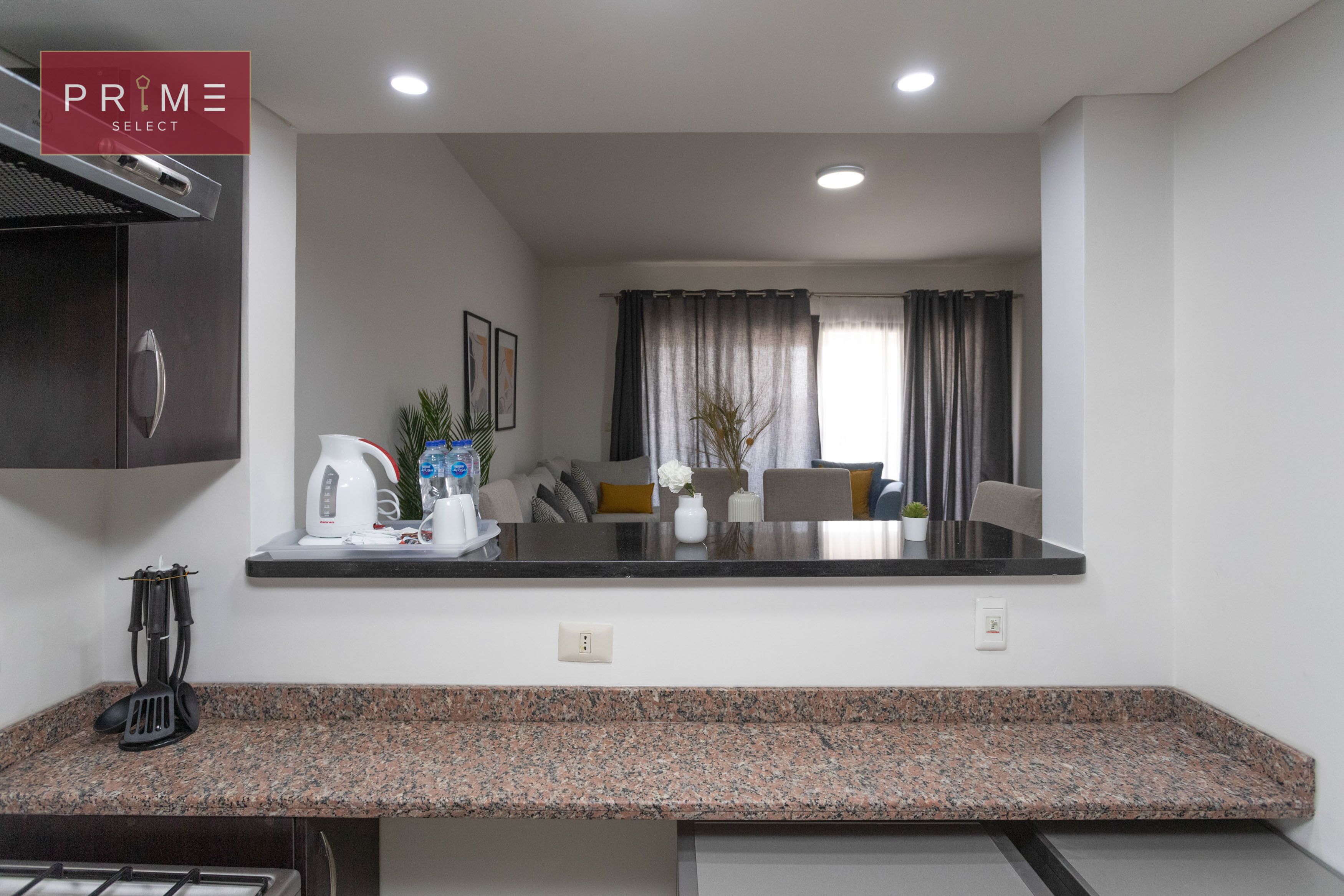 A modern kitchen with granite countertops, a built-in oven, and a stainless steel range hood.