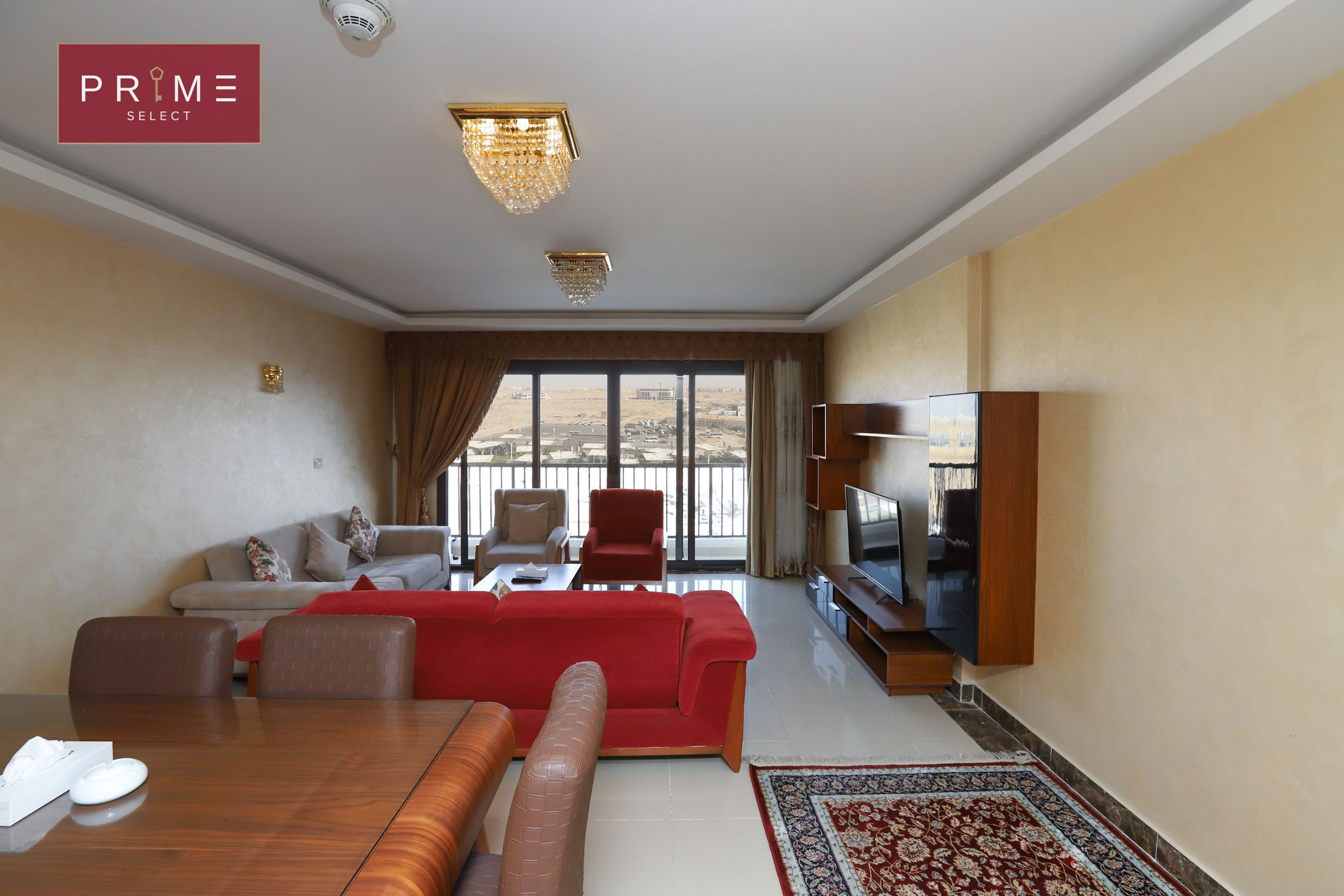 Un salón amplio con un sofá rojo, una mesa de comedor de madera y un televisor sobre un mueble de madera.