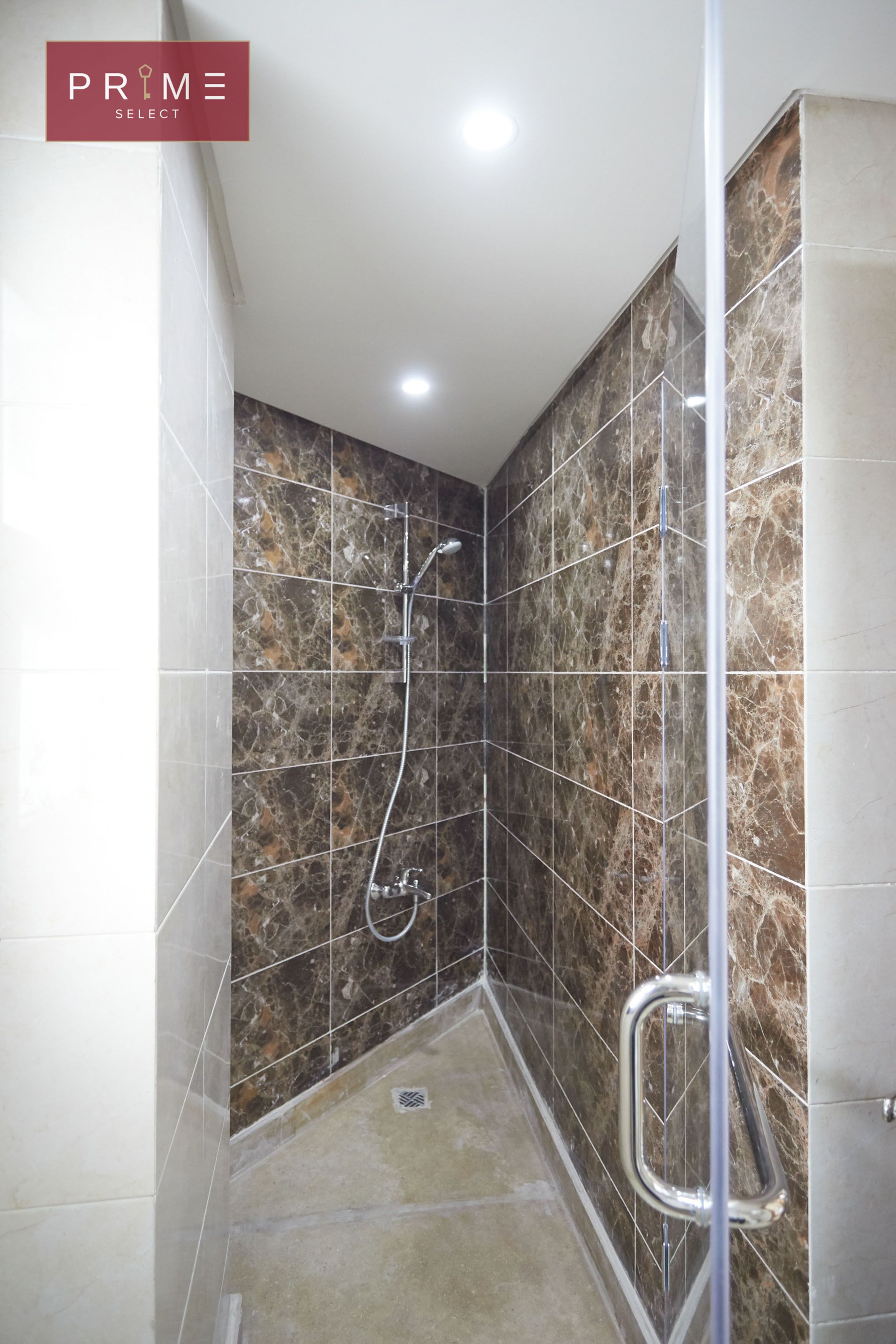Een moderne badkamer met een douche, betegelde wanden en een glazen deur.
