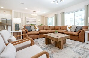 Un salon moderne avec un canapé d’angle, une table basse et un coin repas.