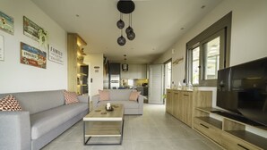 A modern living room with a grey sofa, a wooden coffee table, and a TV on a wooden stand. - Royal Hill Villa (Hersonissos)