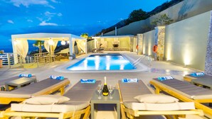 A pool area with lounge chairs and a hot tub, surrounded by stone walls and a view of the sea. - Royal Hill Villa (Hersonissos)