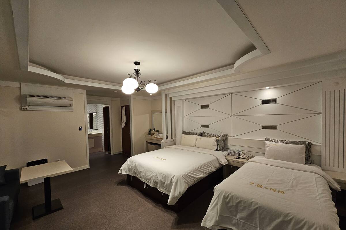A hotel room with two beds, a desk, and a bathroom.