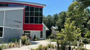 A building with a red and grey facade, labeled "John Dennis Murray Arts Building."