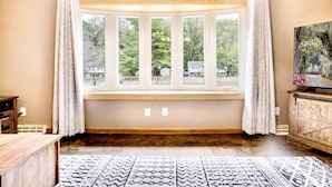 A room with a bay window, a wooden cabinet, and a patterned rug.