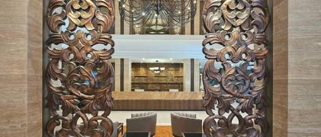 A lobby with ornate wooden partitions, a chandelier, and seating area.