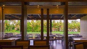 Un ristorante con vista su palme e un giardino tropicale.