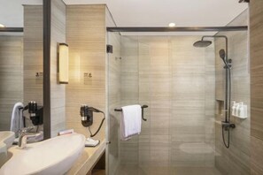 A modern bathroom with a glass-enclosed shower, a sink with a mirror, and toiletries on the wall. - Swiss-Belhotel Airport Yogyakarta (Temon)