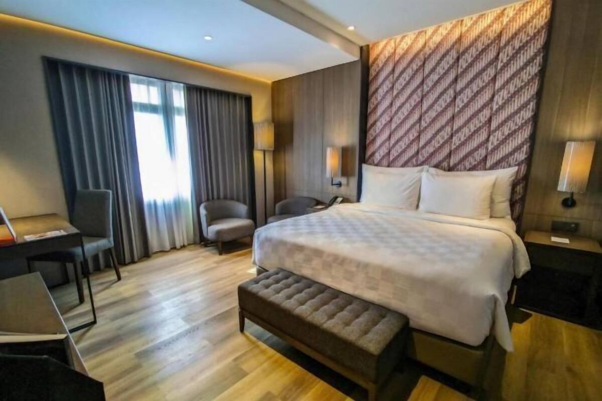 Una habitación de hotel moderna con una cama grande, un escritorio, una silla y un banco.